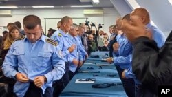 Kosovski policajci srpske nacionalnosti skidaju uniforme, simbolično pokazujući da napuštaju službu, na skupu u Zvečanu 5. novembra 2022.