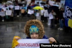 Dijete drži plakat na demonstracijama u Kijevu na kojem su okupljeni tražili usvajanje zakona koji reguliše dužinu aktivnog vojnog roka i učestalost rotacije na frontu, 12. novembra 2023.