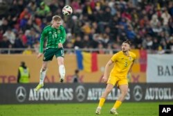 Radu Dragušin (desno) dok sjevernoirski reprezentativac Trai Hume udara loptu glavom tokom prijateljske utakmice sa Sjevernom Irskom na stadionu u Bukureštu, mart 2024