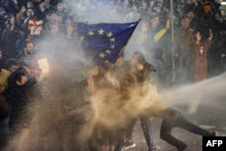 Demonstranti koji mašu zastavom EU gađani su vodenim topom tokom sukoba s interventnom policijom u blizini gruzijskog parlamenta u Tbilisiju 7. marta. Hiljade ljudi izašlo je na ulice glavnog grada protiveći se kontroverznom zakonu o "stranim agentima".