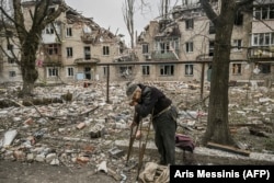 Житель Авдеевки на фоне разрушенного обстрелами дома, 23 марта 2023 года