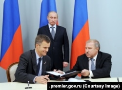 Ruski predsjednik Vladimir Putin (stoji) prisustvuje potpisivanju sporazuma o strateškoj saradnji između tadašnjeg predsjednika uprave Rosnefta Eduarda Hudainatova (desno) i tadašnjeg predsjednika uprave Statoil ASA Helgea Lunda 5. maja 2012.