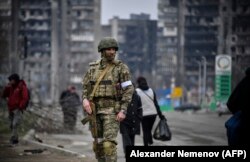 A Russian soldier patrols a street in the devastated Ukrainian city of Mariupol in April.
