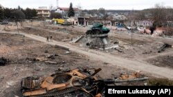 Уничтоженный российский танк в украинском городе Тростянец. На заднем плане – монумент, посвященный Второй мировой войне. 28 марта 2022 года