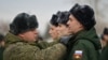 A Russian soldier adjusts the uniform of a conscript at a gathering point before departure for garrisons in Omsk, Russia.