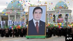 Adamlar Türkmenistanyň prezidenti Gurbanguly Berdimuhamedowyň äpet portretini göterip barýarlar.