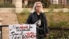Margarita Murakhtayeva stood at the site where her mother burned to death on October 2, 2020, with a poster saying, "My mother would say 'Putin, go to hell with your war,' but Putin already killed her."