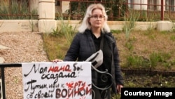 Margarita Murakhtayeva stood at the site where her mother burned to death on October 2, 2020, with a poster saying, "My mother would say 'Putin, go to hell with your war,' but Putin already killed her."