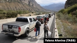 People walk by a line of vehicles on the road for the Verkhny Lars checkpoint on the Russian-Georgian border in September 2022. According to the Georgian Interior Ministry, around 78,000 Russians arrived in Georgia from September 17-26. 