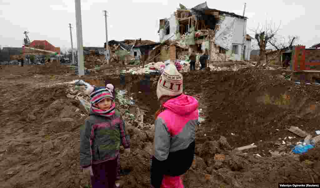 Deca stoje pored kratera koji je ostavio ruski raketni udar u gradu Hlevaha, nedaleko od Kijeva, 26. januara 2023. &nbsp;