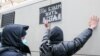 A police officer detains a supporter of the Memorial society, which Russia has deemed a foreign agent, outside the Moscow Supreme Court in December 2021. The supporter holds a sign reading, "We will live always."