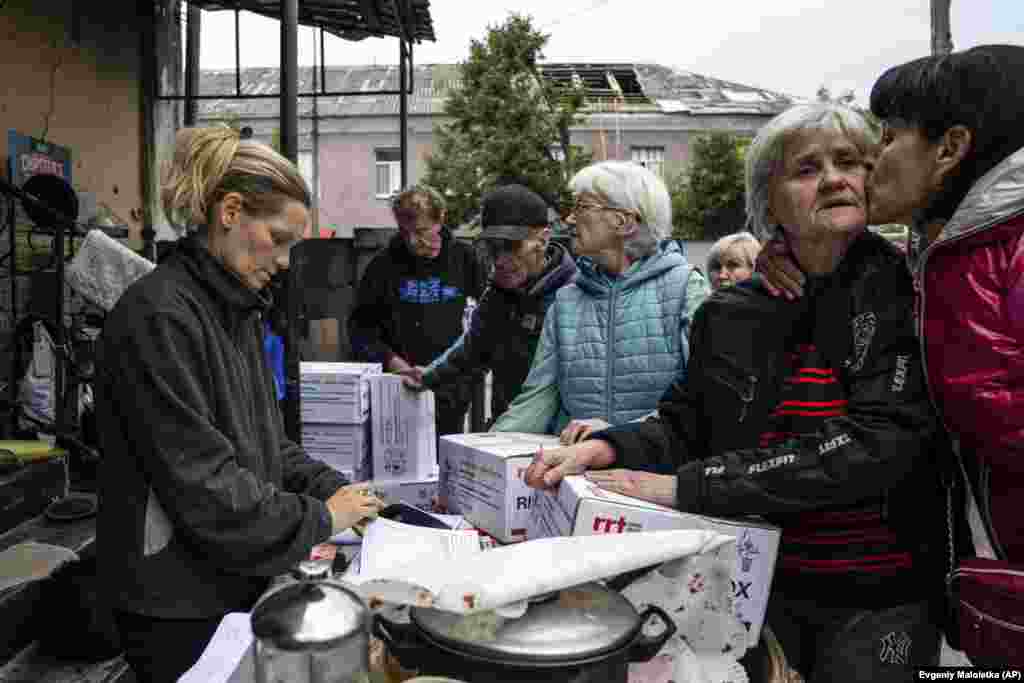Žena ljubi drugu ženu dok čekaju u redu da prime humanitarnu pomoć u nedavno ponovo oslobođenom gradu Izjumu.