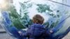 Dijete grli balon u obliku planete Zemlje tokom okupljanja u povodu početka Konferencije za klimatske promjene (COP21), Rim, Italija, 2015.
