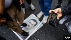 Demonstrant gazi po fotografiji Bašara al-Asada tokom protesta ispred sirijskog konzulata u Istanbulu, Turska, 8. 12. 2024.