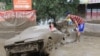 People examine a car damaged by the landslide in Almaty.