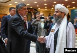 რუსეთის პრეზიდენტის ელჩი ავღანეთში, ზამირ ქაბულოვი (მარცხნივ), ოქტომბერში მოსკოვში ავღანეთის შესახებ საერთაშორისო მოლაპარაკებების დაწყებამდე ხელს ართმევს თალიბანის დელეგაციის წარმომადგენელს მალავი შაჰაბუდდინ დილავარს. 2021 წლის 20 ოქტომბერი.