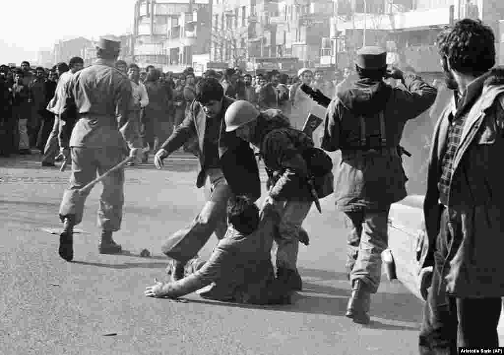 Demostranta s ulice podiže vojnik nakon što ga je palicom udario vojni oficir (lijevo) usred čarke u Teheranu 14. januara, 1979. godine. 