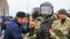 Участник митинга против границы между Чечней и Ингушетией и сотрудники полиции на центральной площади Магаса, октябрь 2018 года 