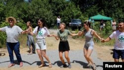 Greta Tunberg(u sredini) pleše tradicionalni narodni ples s lokalnim aktivistima koji protestuju protiv projekata hidroelektrana u planinskom području Kožufa u blizini Đevđelije, Sjeverna Makedonija, 26. jula 2025. 