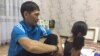 Maksat Dosmaghambetov (left) sits with his daughter at home in Zhanaozen on September 30, 2017.