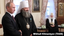 რუსეთის პრეზიდენტი პუტინი ჯილდოს გადასცემს კიევ-პეჩორის ლავრის აწ უკვე ყოფილ წინამძღვარს, მიტროპოლიტ პავლეს. ღონისძიებას ესწრება რუსეთის პატრიარქი კირილე. 27 ივლისი, 2013 წელი. 