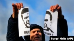 Demonstrant drži rastrgani portret tadašnjeg ukrajinskog predsjednika Viktora Janukoviča i uzvikuje "Kukavica!" na skupu 29. novembra.