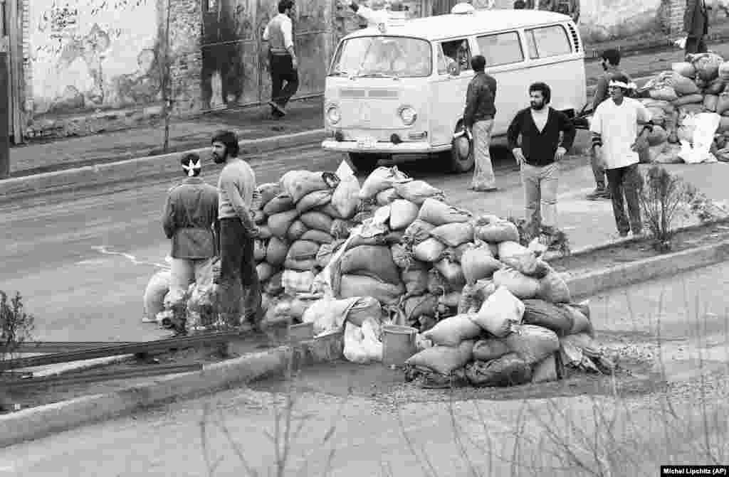Ambulantna kola prolaze pored barikade od vreća s pjeskom kako bi pokupila ranjene ljude na ulicama nastradalim u nemirima od 10. februara, 1979. U pucnjavi između vojske, kadeta vazduhoplovstva i Homeinijevih pristalica nastradalo je na stotine ljudi a 60 ih je umrlo. 