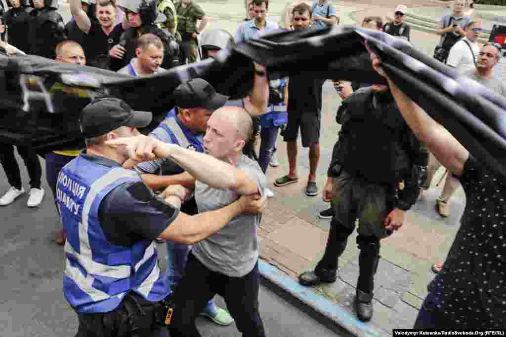 An anti-LGBT protester scuffles with security personnel at the Kyiv march.