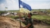 Ілюстраційне фото. Український військовослужбовець тримає понівечений кулями прапор України на позиції біля міста Мар'їнка. Червень 2015 року