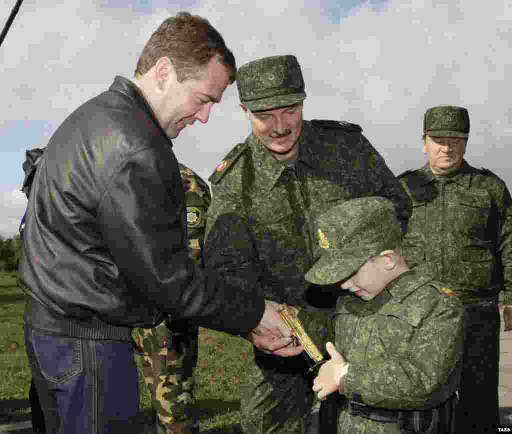 Ruski predsjednik Dmitrij Medvedev (lijevo) i njegov bjeloruski kolega Aleksandar Lukašenko s petogodišnjim sinom bjeloruskog predsjednika Mikalajem dok dječak gleda zlatni pištolj, 2009. Pištolj je bio poklon Medvedeva.