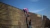 Migranti prelaze ogradu na granici sa Meksikom