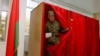 A soldier leaves a voting booth in Minsk to cast his ballot during early voting for Belarus's parliamentary elections.
