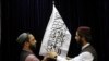 Talibanski zvaničnici postavljaju zastavu talibana pre početka konferencije za novinare 17. avgusta na kojoj su pokušali da ublaže strahve da će ponovo vratiti represivan režim kao kada su prethodno kontrolisali Avganistan od 1996. do 2001.