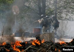 Ukrainian security troops walk past a checkpoint set on fire and vacated by pro-Russian separatists near Slovyansk.