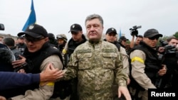 Ukrainian President Petro Poroshenko makes his way during a meeting with local residents in the eastern Ukrainian town of Slovyansk on July 8, after it was reportedly retaken from separatists.