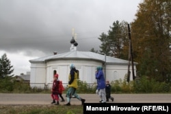 Tajik women collect their children from a kindergarten near a church in Rozhdestveno.