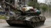 UKRAINE – Service members of pro-Russian troops drive a tank along a street past a destroyed residential building during Ukraine-Russia conflict in the town of Popasna in the Luhansk Region, May 26, 2022