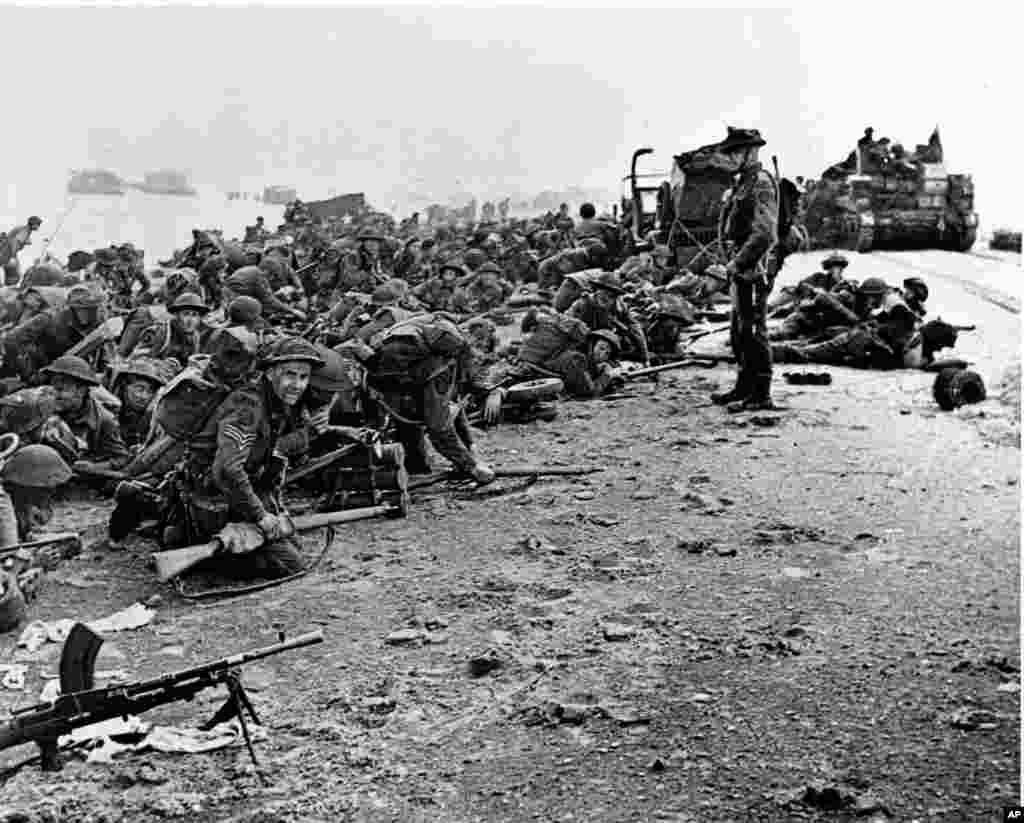 Nakon što su stigli na obalu, pripadnici britanskih trupa čekaju signal da krenu napred, tokom početnih operacija iskrcavanja saveznika u Normandiji, Francuska. (6. jun 1944.) &nbsp;
