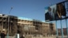 "Өзенмұнайгаз" компаниясының өртеніп кеткен ғимараты мен Назарбаевтың жарнамасы. Жаңаөзен, 19 желтоқсан 2011 жыл. 