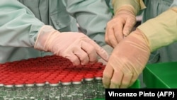 Laboratorijski tehničari rukuju zatvorenim bočicama kao dio testova punjenja i pakovanja za veliku proizvodnju i opskrbu Univerziteta u Oxfordu