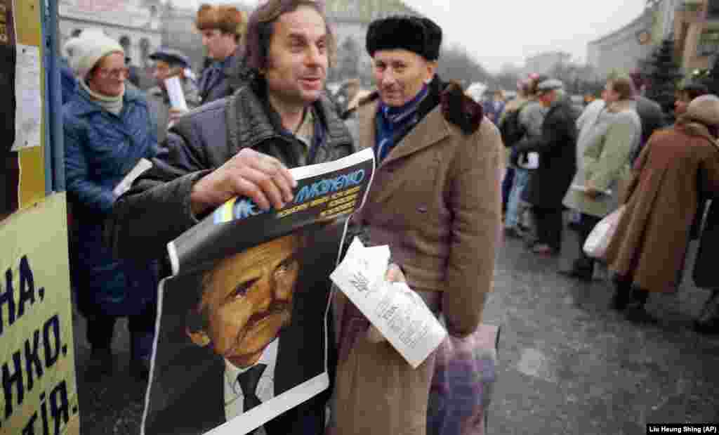 Jedan od pristalica nosi predizborni poster bivšeg disidenta Lukjanenka, sada predsedničkog kandidata, u Kijevu. &nbsp;
