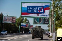 Rusko vojno vozilo prolazi pored plakata sa porukom "Sa Rusijom zauvijek, 27. septembar", u Lugansku, Ukrajina, 22. septembar 2022.