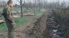 Російський солдат біля розкопаного масового поховання у Чечні