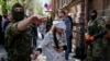 Сепаратист ведет Ирму Крат с завязанными глазами после пресс-конференции в Славянске, 21 апреля 2014 года