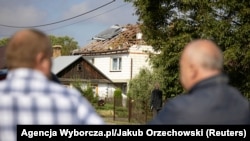 Banorët shikojnë shtëpinë e dëmtuar pasi një dron ose objekt i ngjashëm goditi ndërtesën banimi.