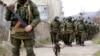 Ukraine -- Armed men, believed to be Russian servicemen, walk outside a Ukrainian military base in Perevalnoye, near the Crimean city of Simferopol, March 14, 2014. 