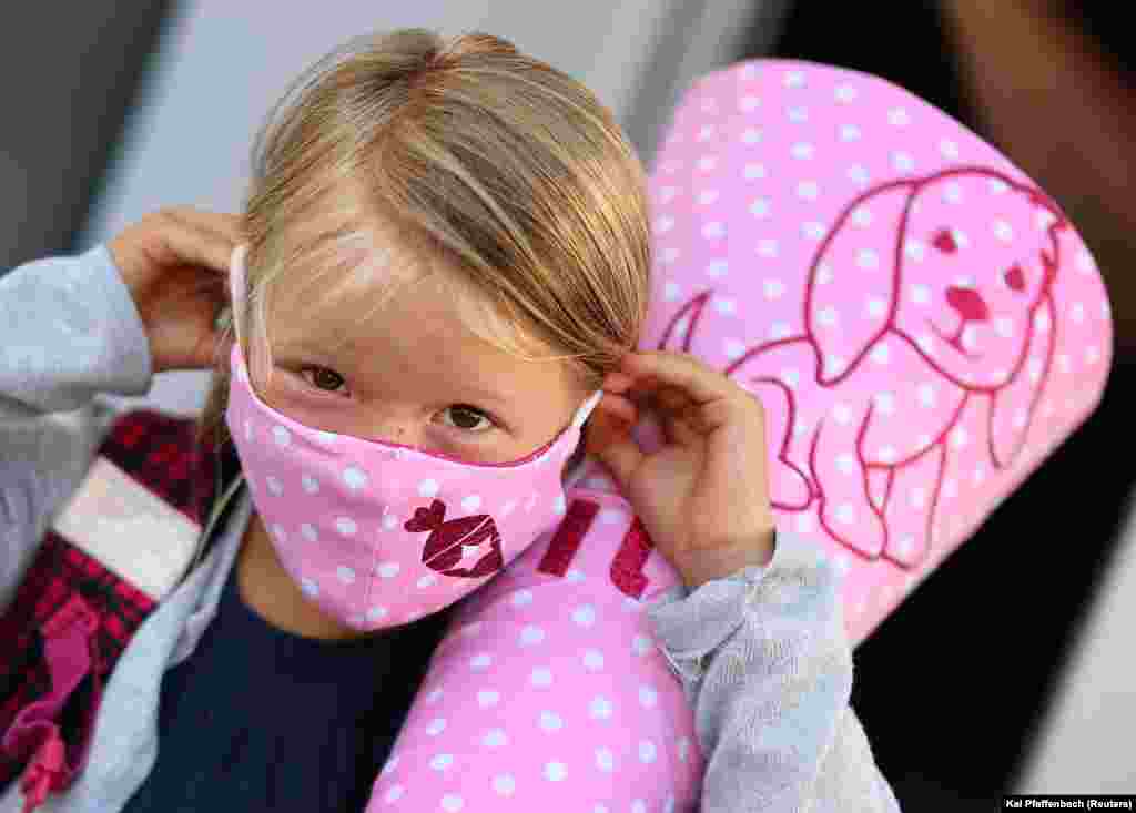 Šestogodišnja Tilda namješta masku za lice prije nego što uđe u osnovnu školu prvi put nakon zatvaranja u Rodenbahu, Njemačka, 18. avgust. Škole u Njemačkoj su se ponovo otvorile od početka avgusta dok je broj zaraženih starosti ispod 20 godina bio stabilan.
