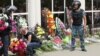 A woman places flowers as Interior Ministry troops stand guard outside a gun shop that was attacked during the funeral of salesman Andrei Maksimenko in Aqtobe on June 8.